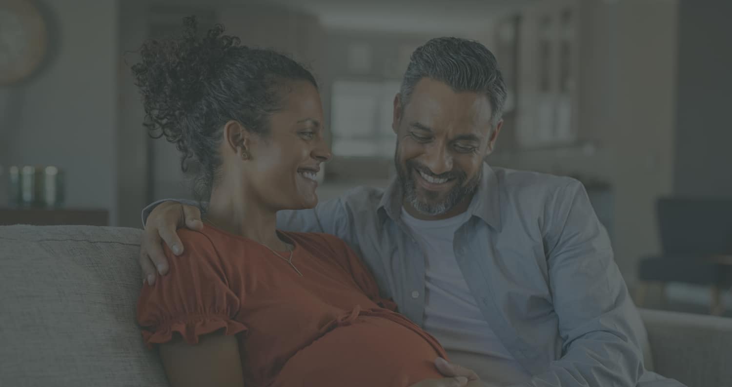 A pregnant woman and man smiling together